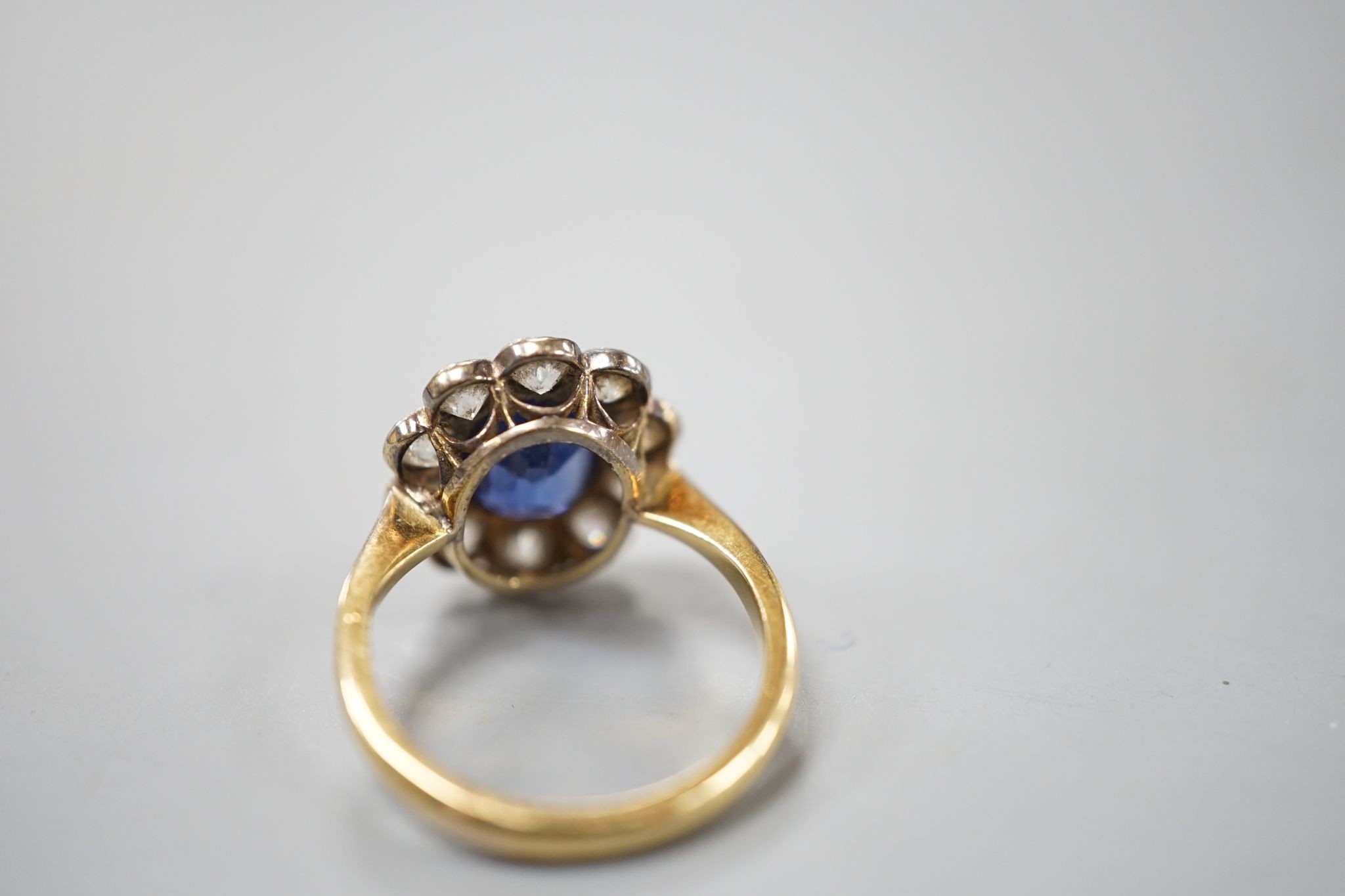 An 18ct gold and platinum, synthetic sapphire and diamond set oval cluster ring